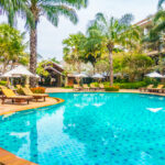 Beautiful luxury swimming pool with palm tree and sea background in hotel pool resort - Boost up color Processing